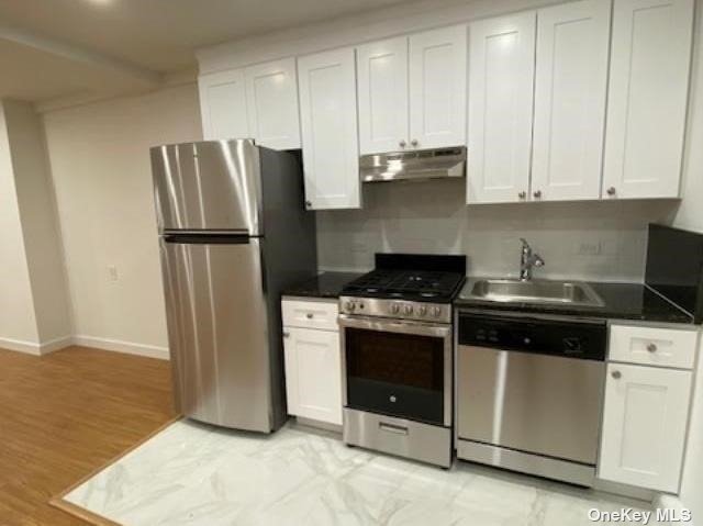 a kitchen with stainless steel appliances granite countertop a refrigerator a stove a sink and white cabinets