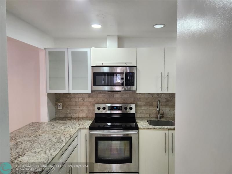 a kitchen with stainless steel appliances granite countertop a stove a microwave and a sink