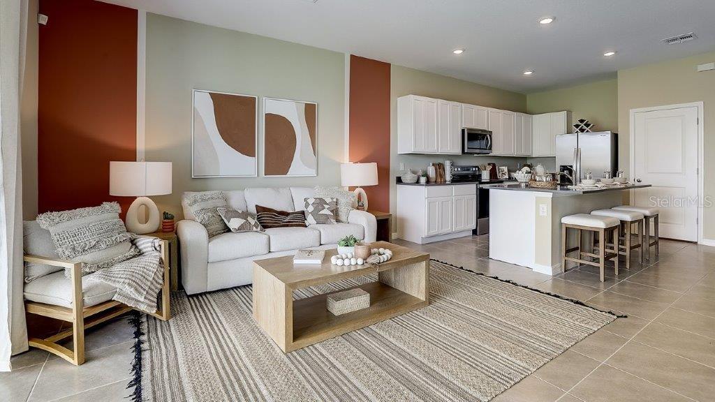 a living room with furniture a rug and kitchen view