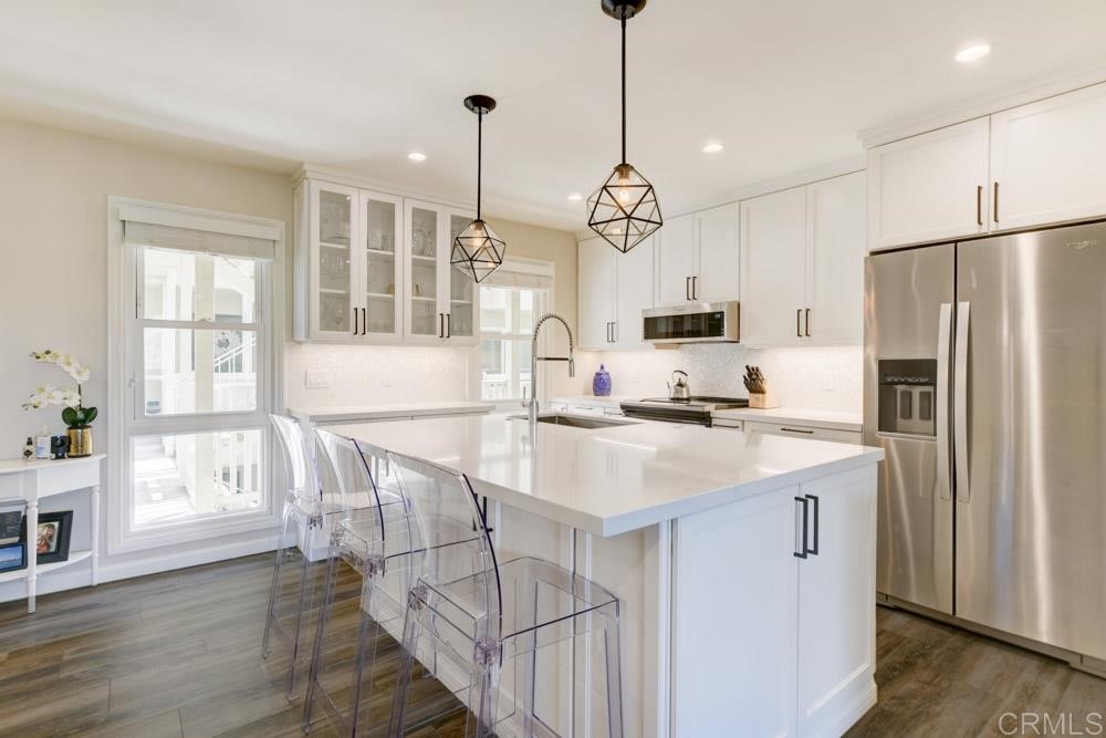 a kitchen with stainless steel appliances kitchen island a refrigerator a stove a sink and a chandelier