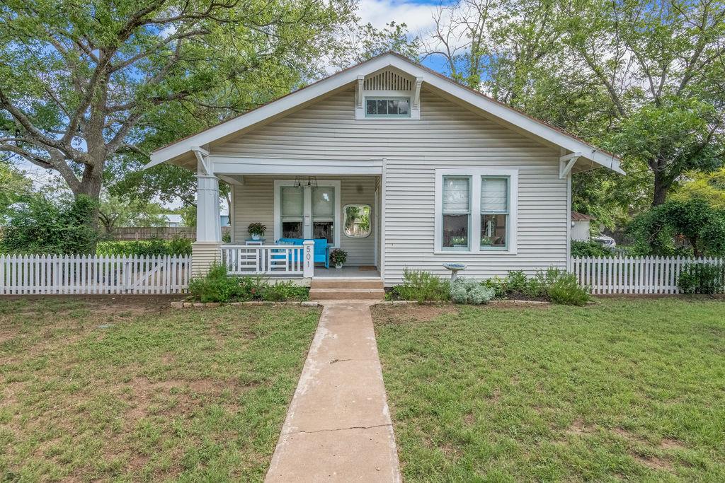 a front view of a house with a yard and potted plants