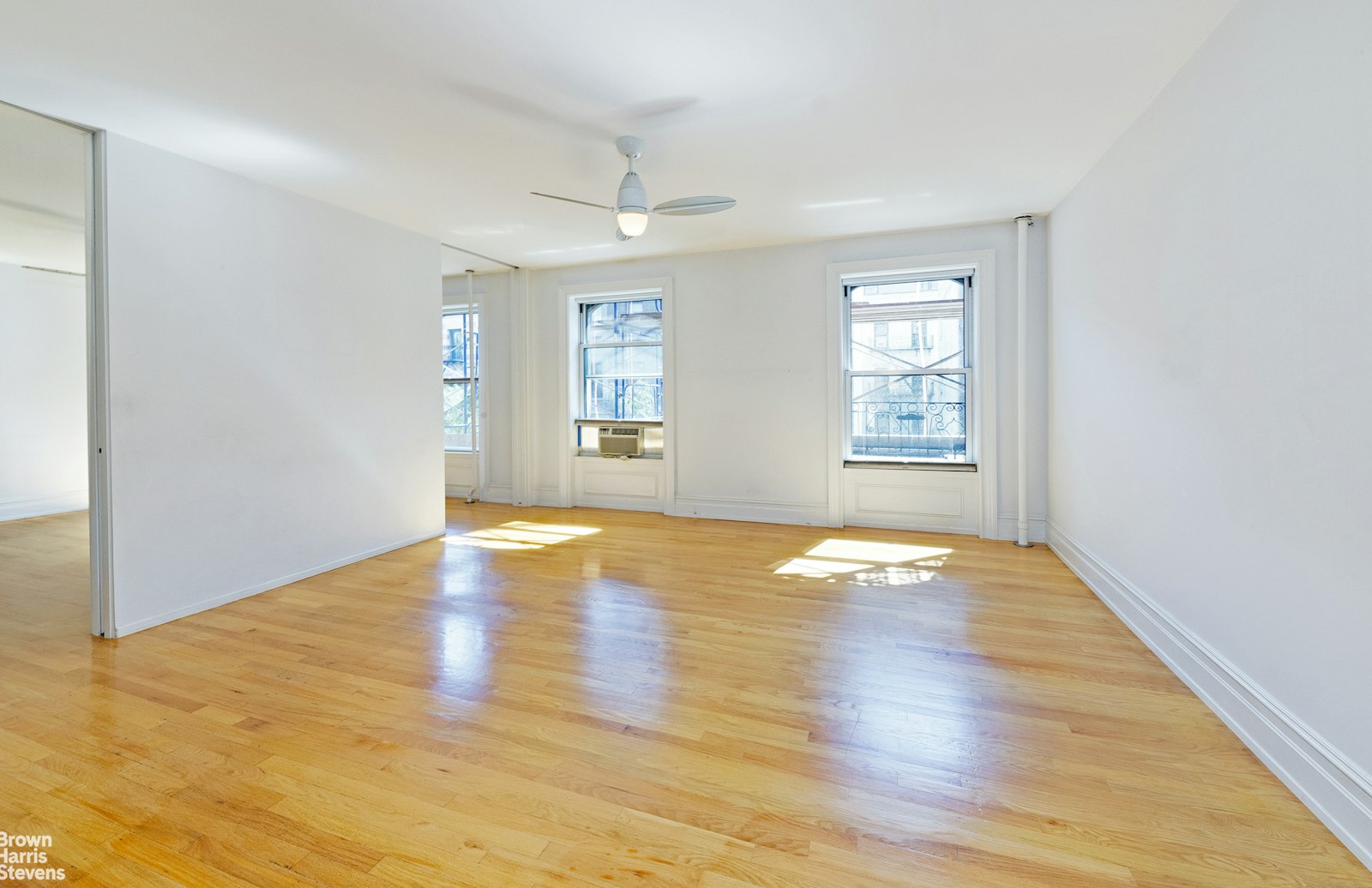 a view of empty room with wooden floor and fan