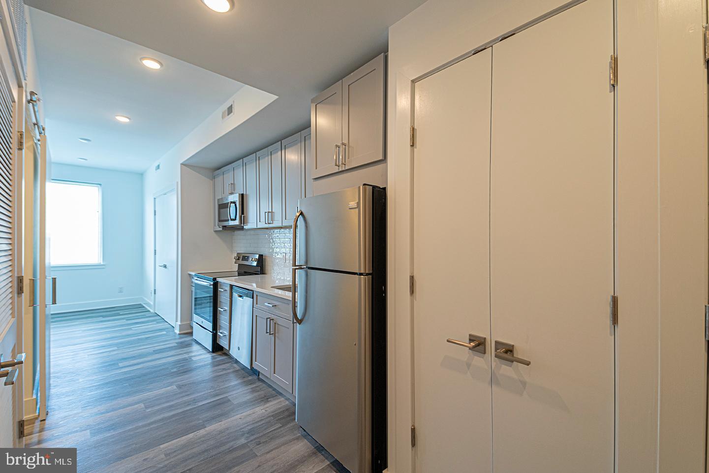 a kitchen with stainless steel appliances a refrigerator and wooden floor