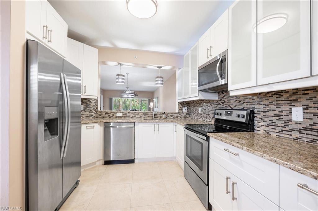 a kitchen with stainless steel appliances granite countertop a refrigerator a stove and a sink