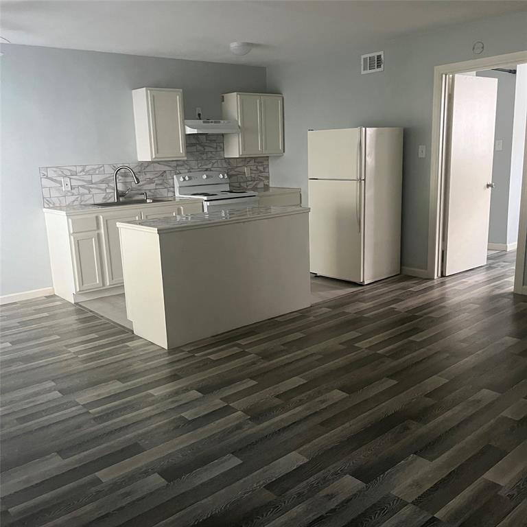 a kitchen with kitchen island wooden floors white cabinets appliances and cabinets