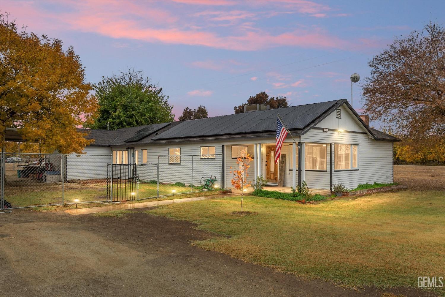 a front view of house with yard and trees in the background