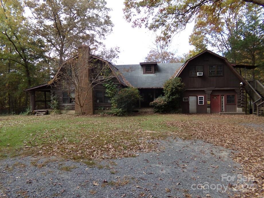 a view of a house with a yard and large tree