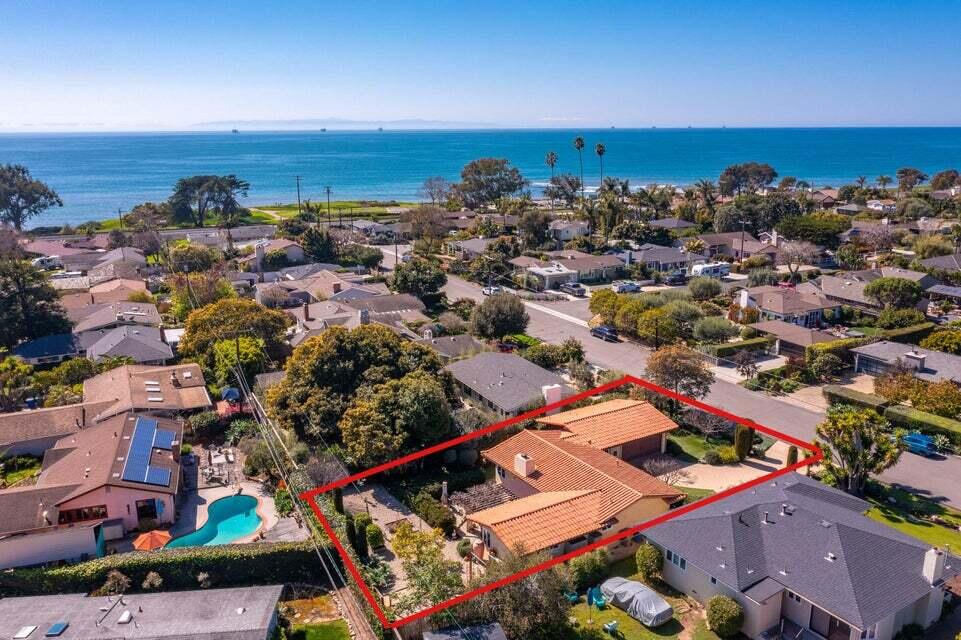 an aerial view of a city with lots of residential buildings and ocean view in back