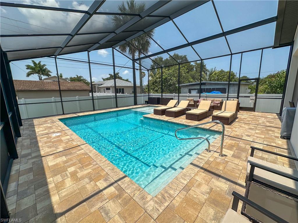 View of swimming pool with glass enclosure and a patio