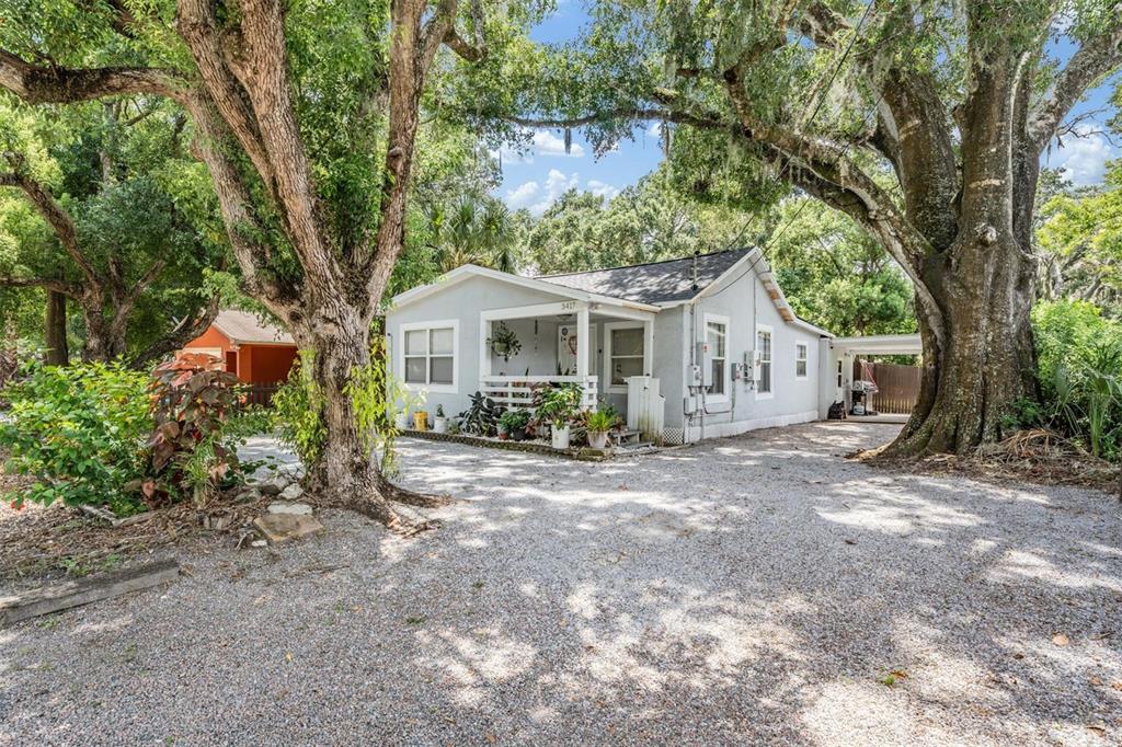 a view of a house with a yard and large trees