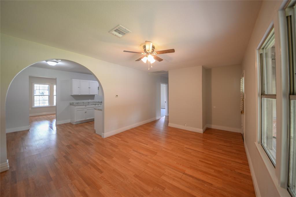 an empty room with wooden floor and a ceiling fan