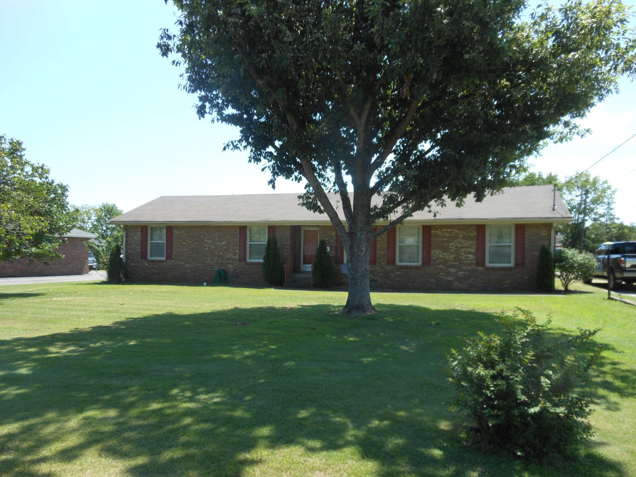 a brick house with a big yard plants and trees