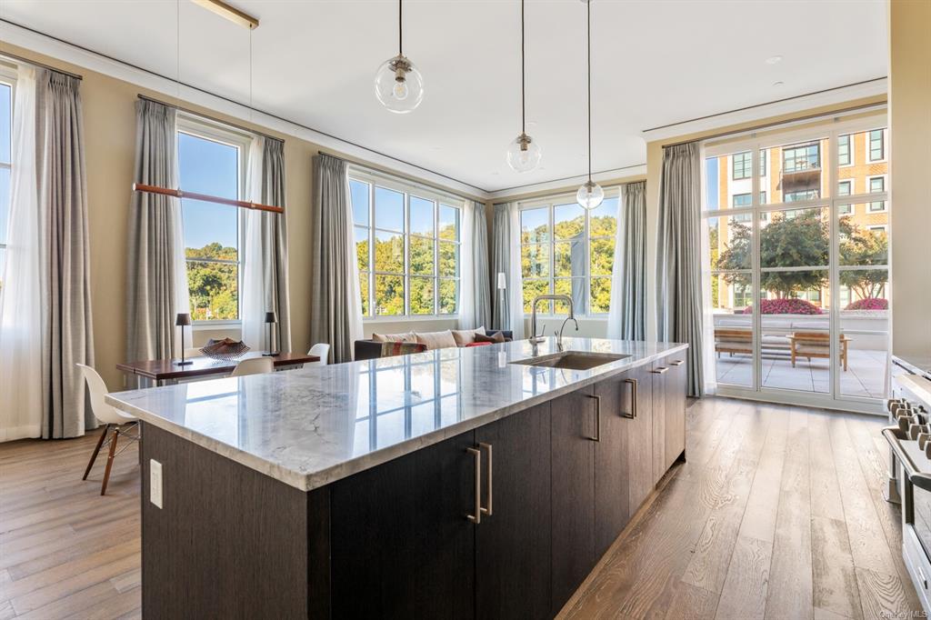 Kitchen with hanging light fixtures, a healthy amount of sunlight, sink, and a center island with sink