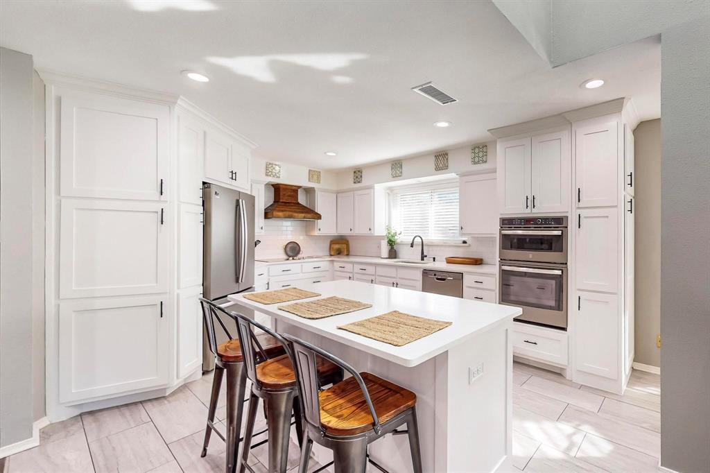 a kitchen with stainless steel appliances kitchen island granite countertop a refrigerator and a stove top oven