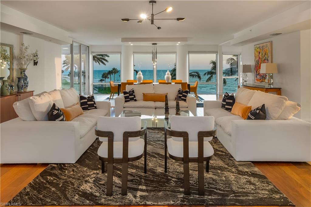 Living room with a healthy amount of sunlight, wood-type flooring, a water view, and a chandelier