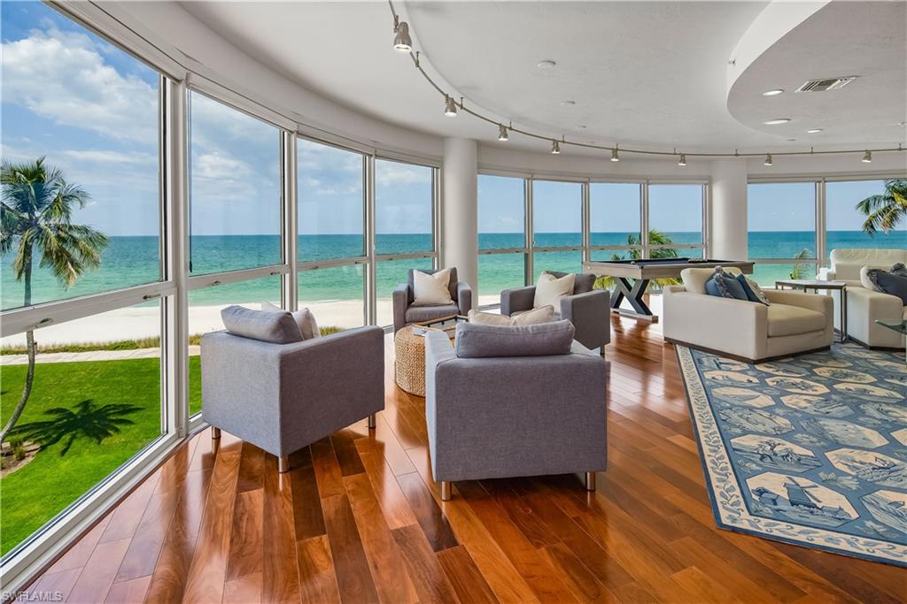 Living room with a wealth of natural light, track lighting, a water view, and dark hardwood / wood-style floors