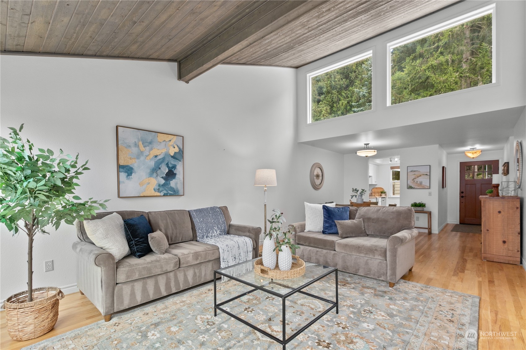 a living room with furniture and a large window with potted plants