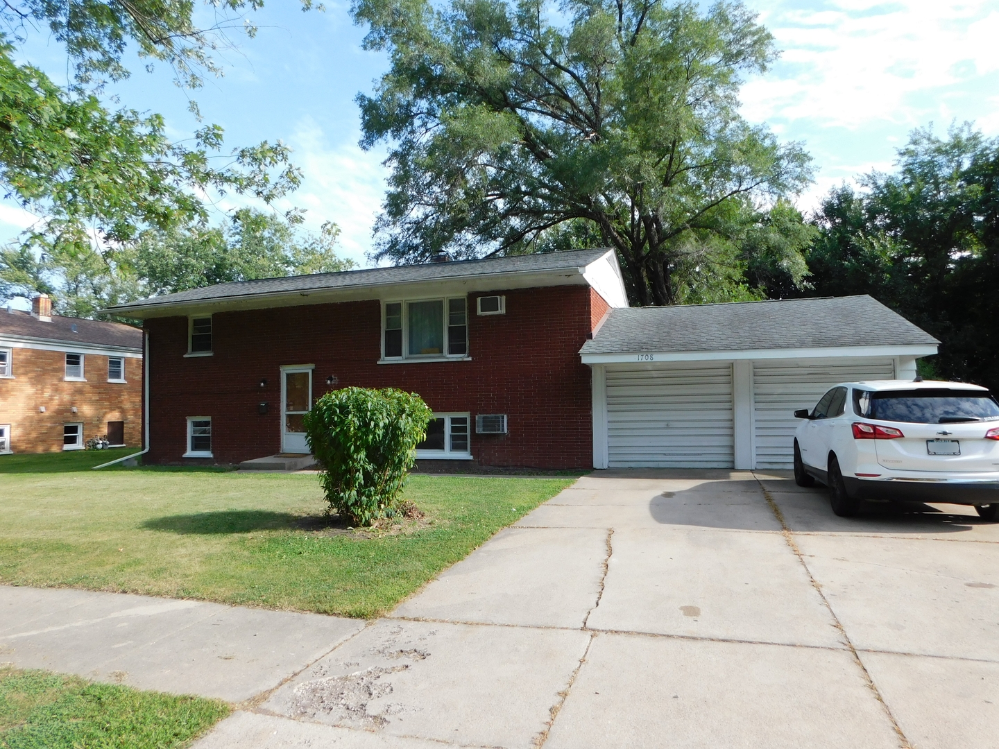 a view of a house with a yard and large trees