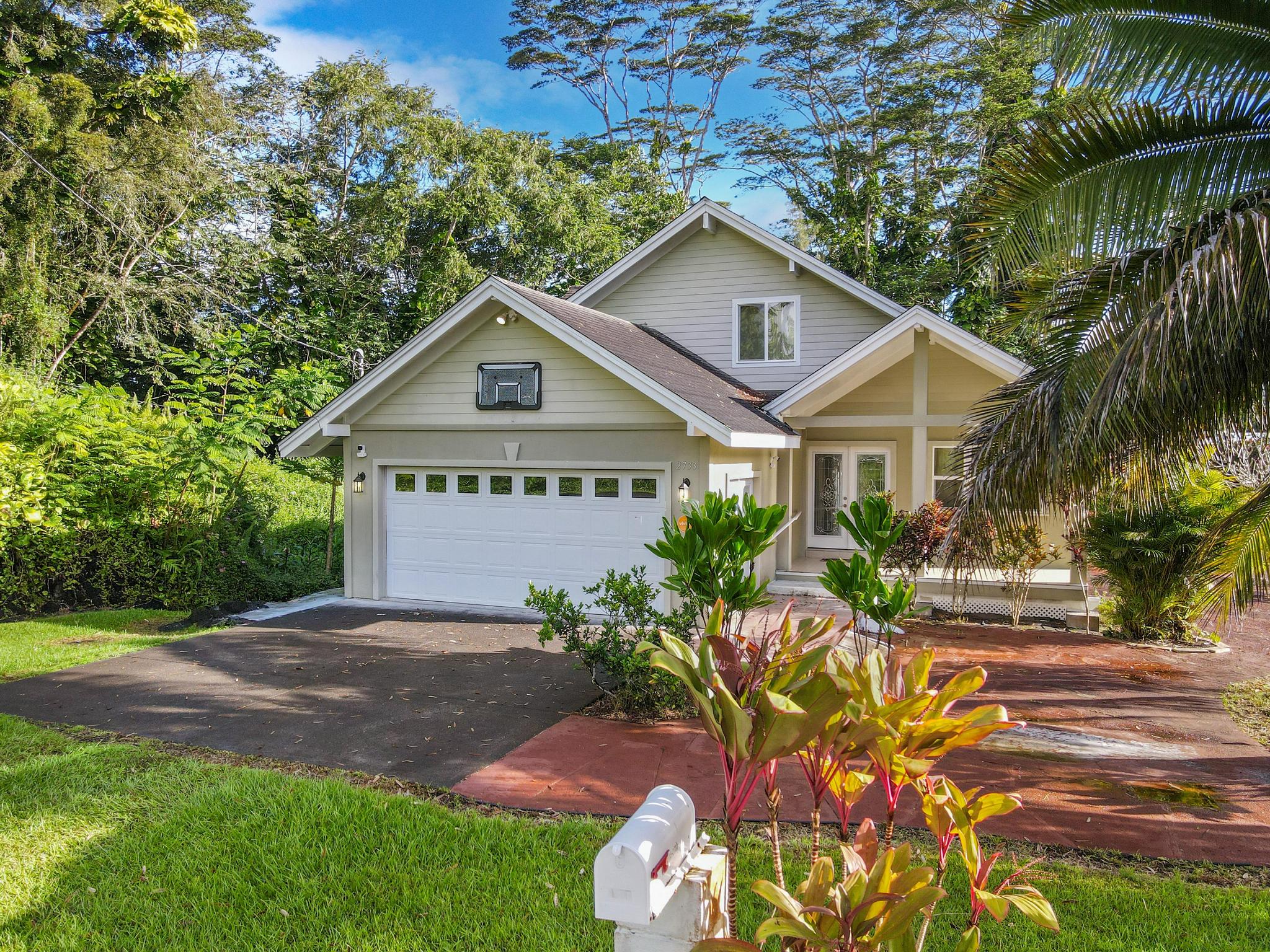 a front view of a house with a yard and a garden