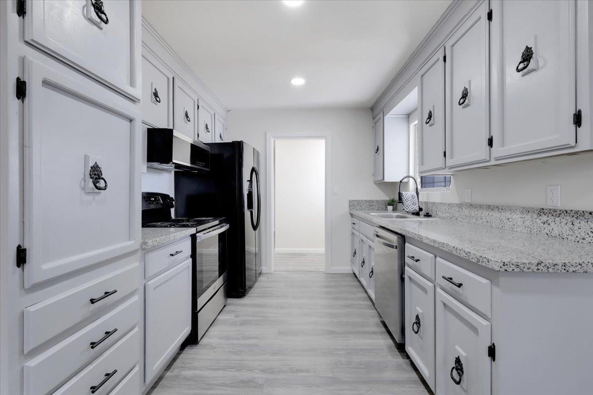 a kitchen with granite countertop a sink stove refrigerator and cabinets