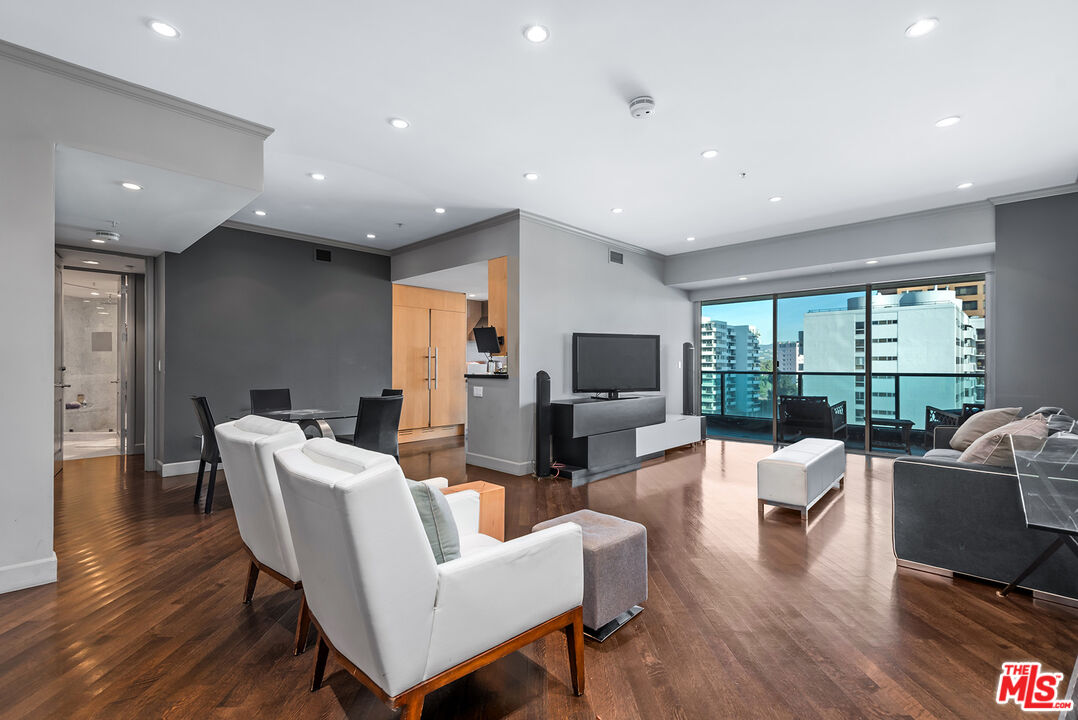 a living room with furniture a large window and wooden floor