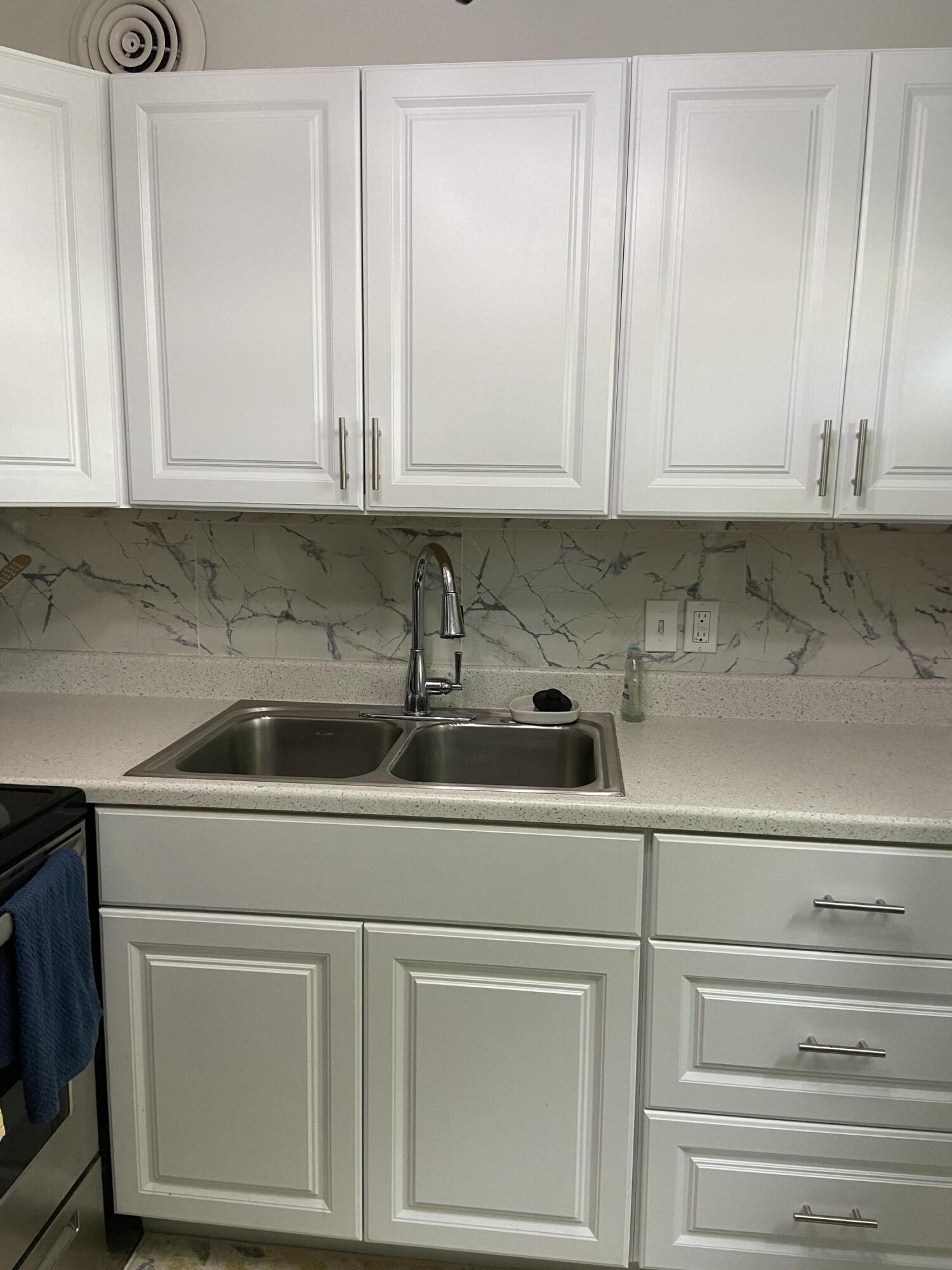 a kitchen with white cabinets and sink