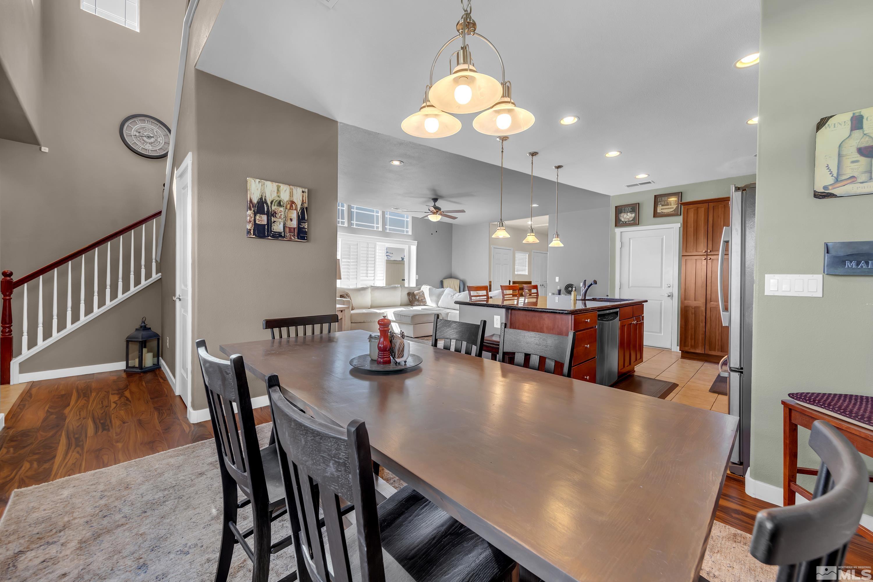 a view of a dining room and livingroom with furniture wooden floor a rug a fireplace and a chandelier