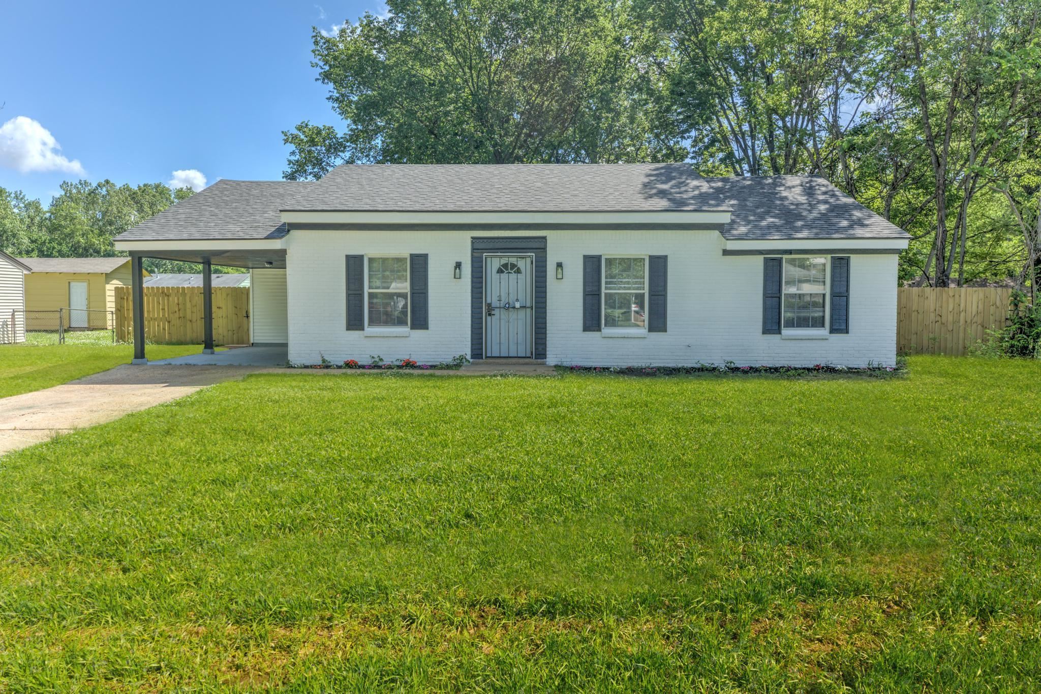 a front view of house with yard and trees in the background