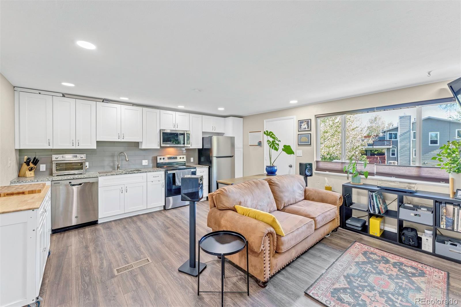 a living room with stainless steel appliances furniture and a kitchen view