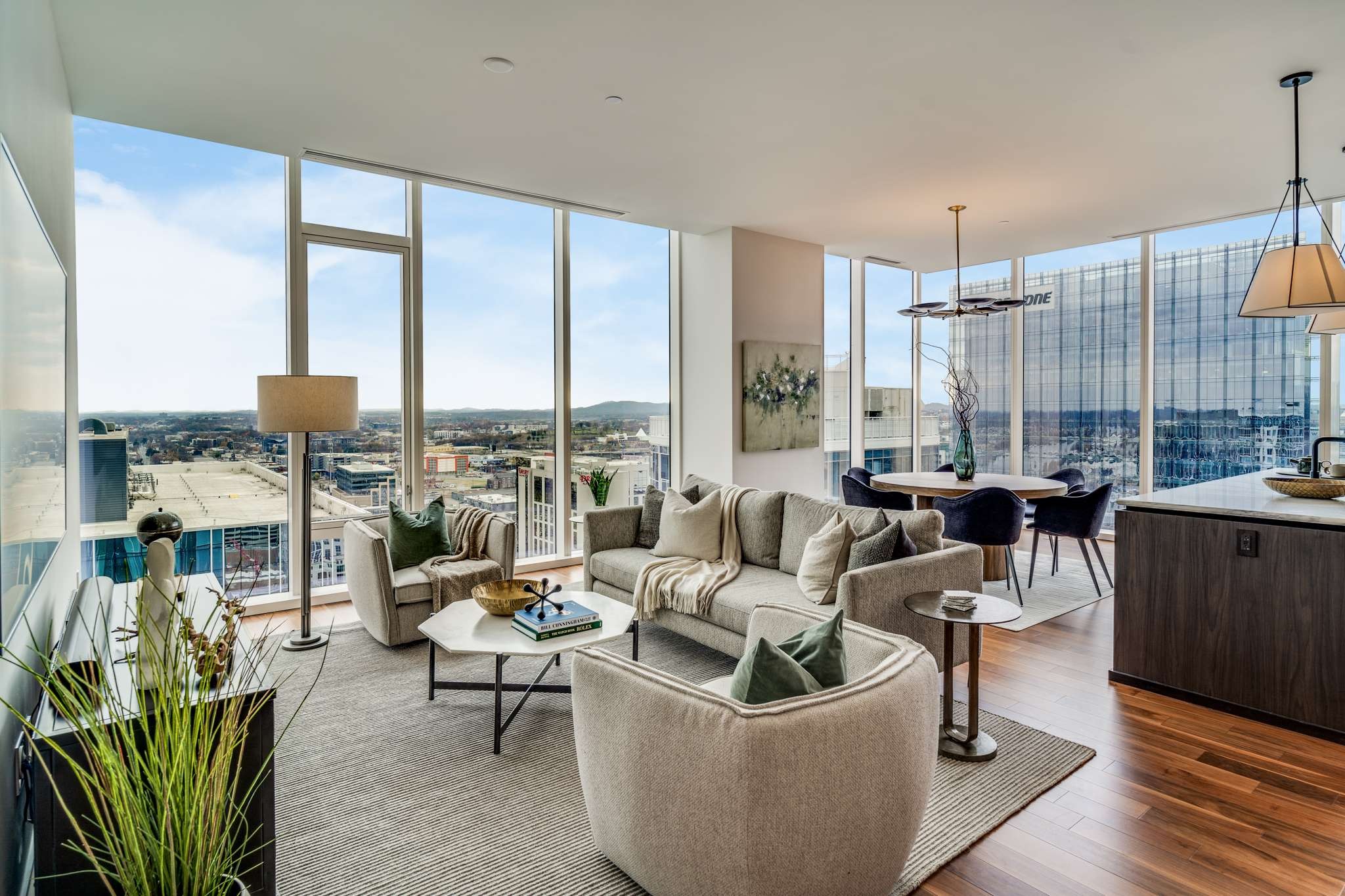 a living room with furniture large windows and wooden floor