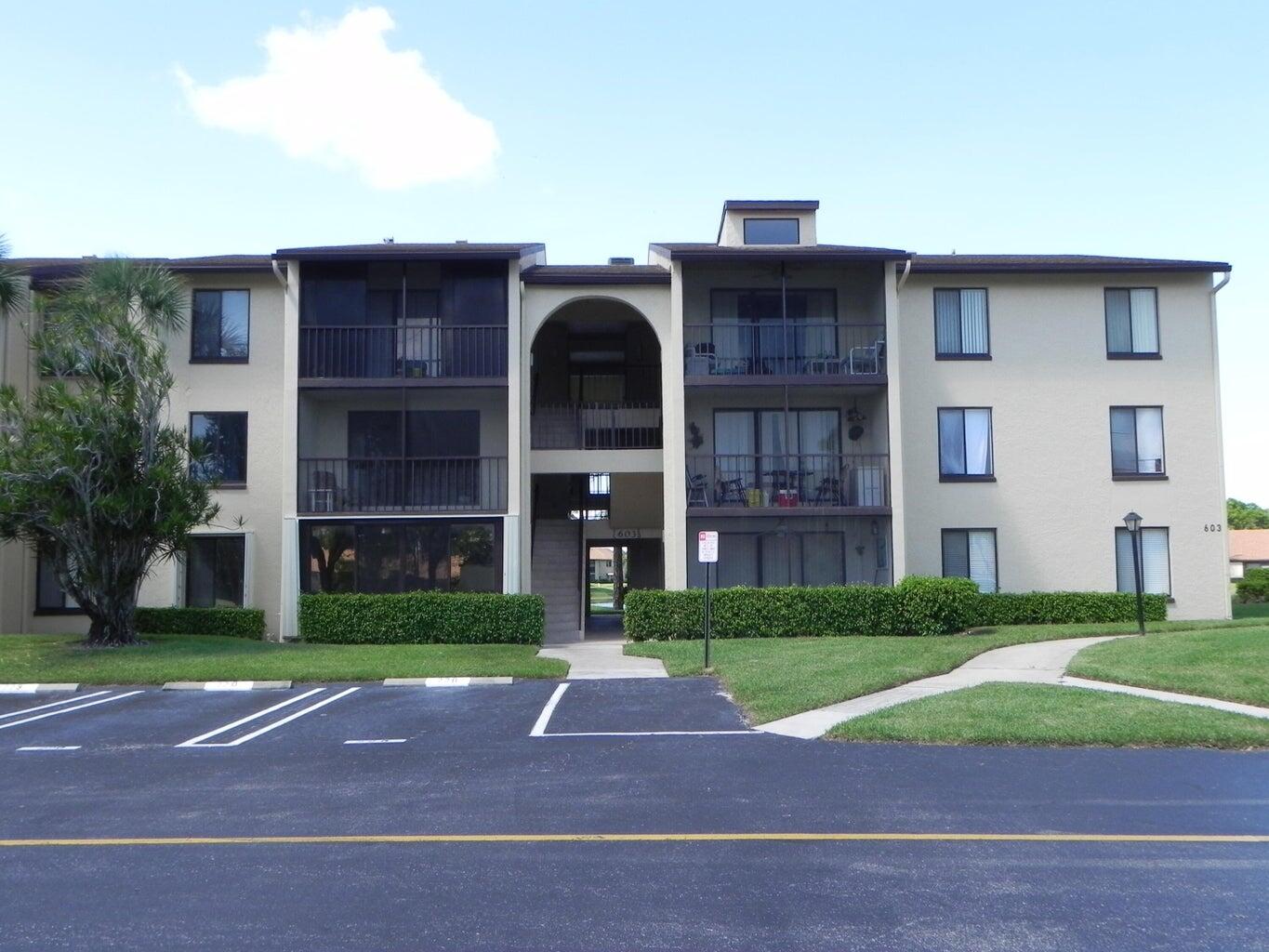 a front view of a building with a yard and trees