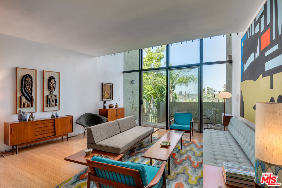 a living room with furniture a rug a large window and a flat screen tv