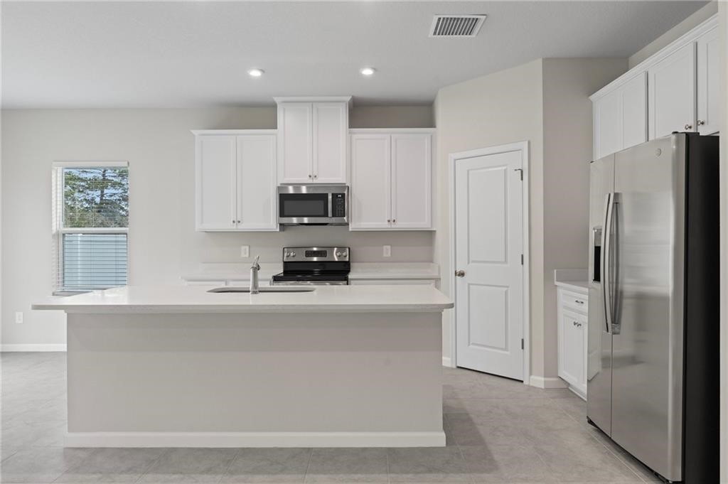 a kitchen with stainless steel appliances a refrigerator sink and white cabinets