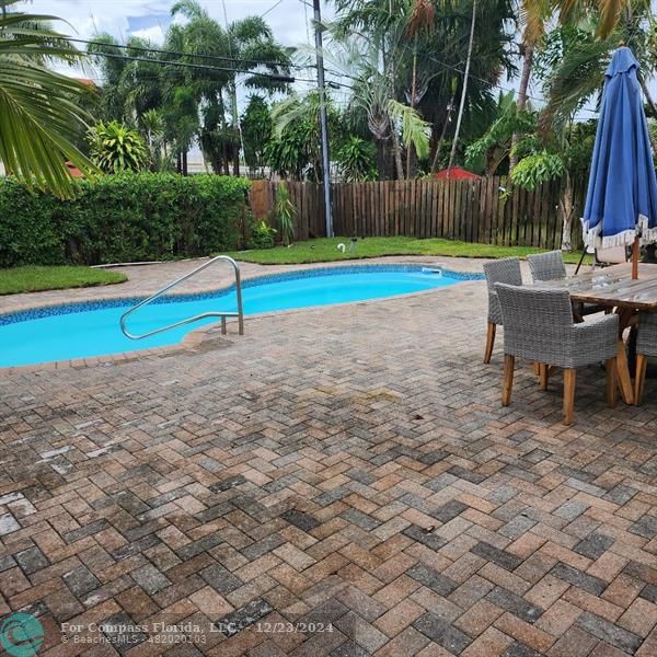 a view of a backyard with swimming pool and sitting area