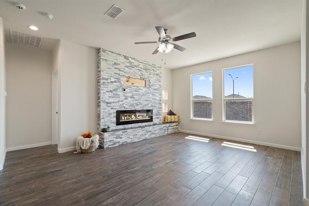 a view of an empty room with wooden floor fireplace and a window