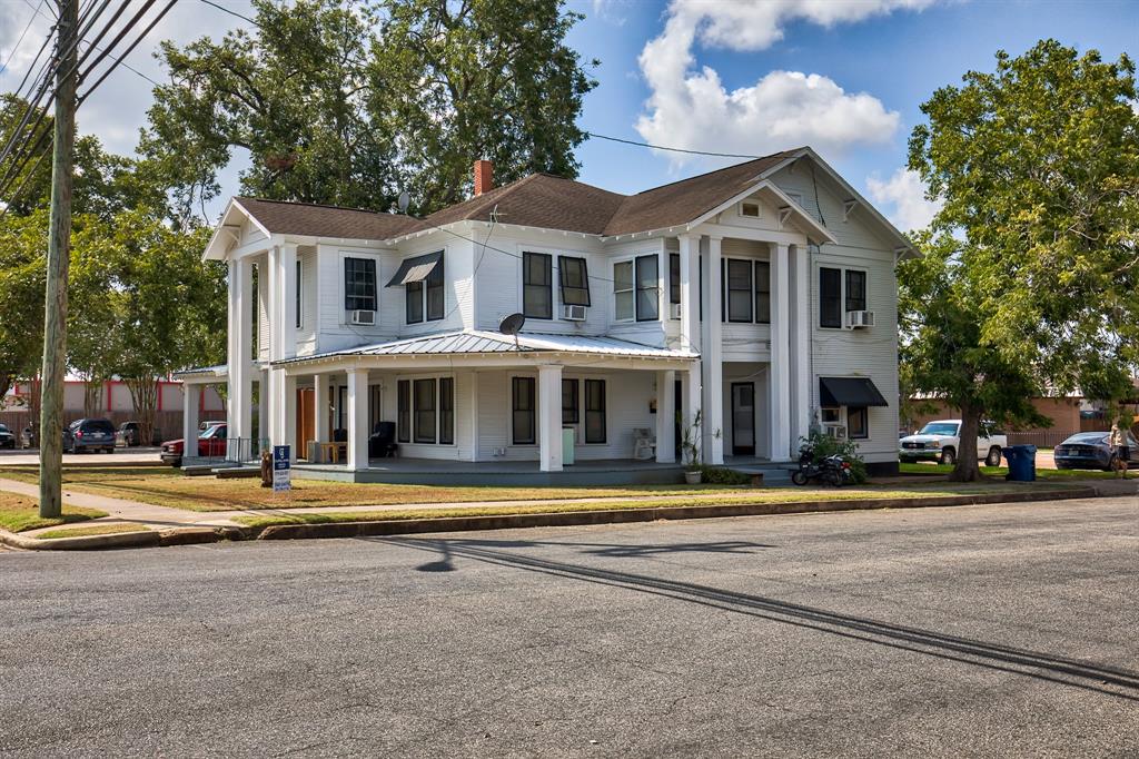 a front view of a building with street view and trees