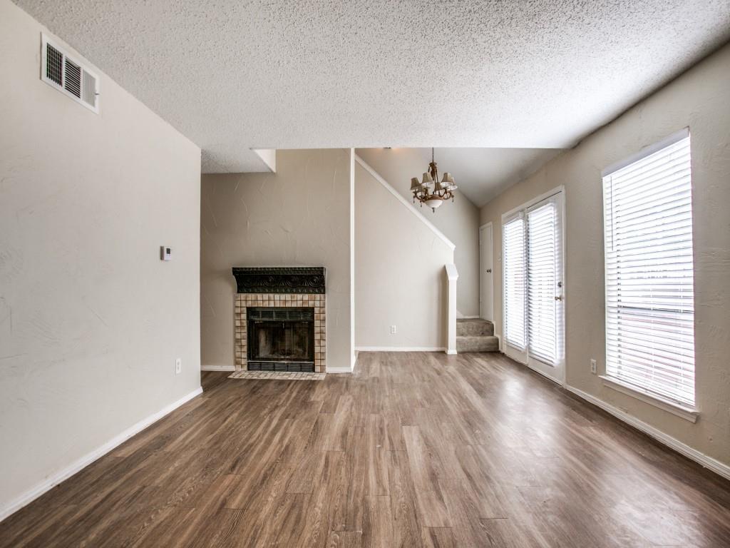 a view of an empty room with wooden floor fireplace and a window