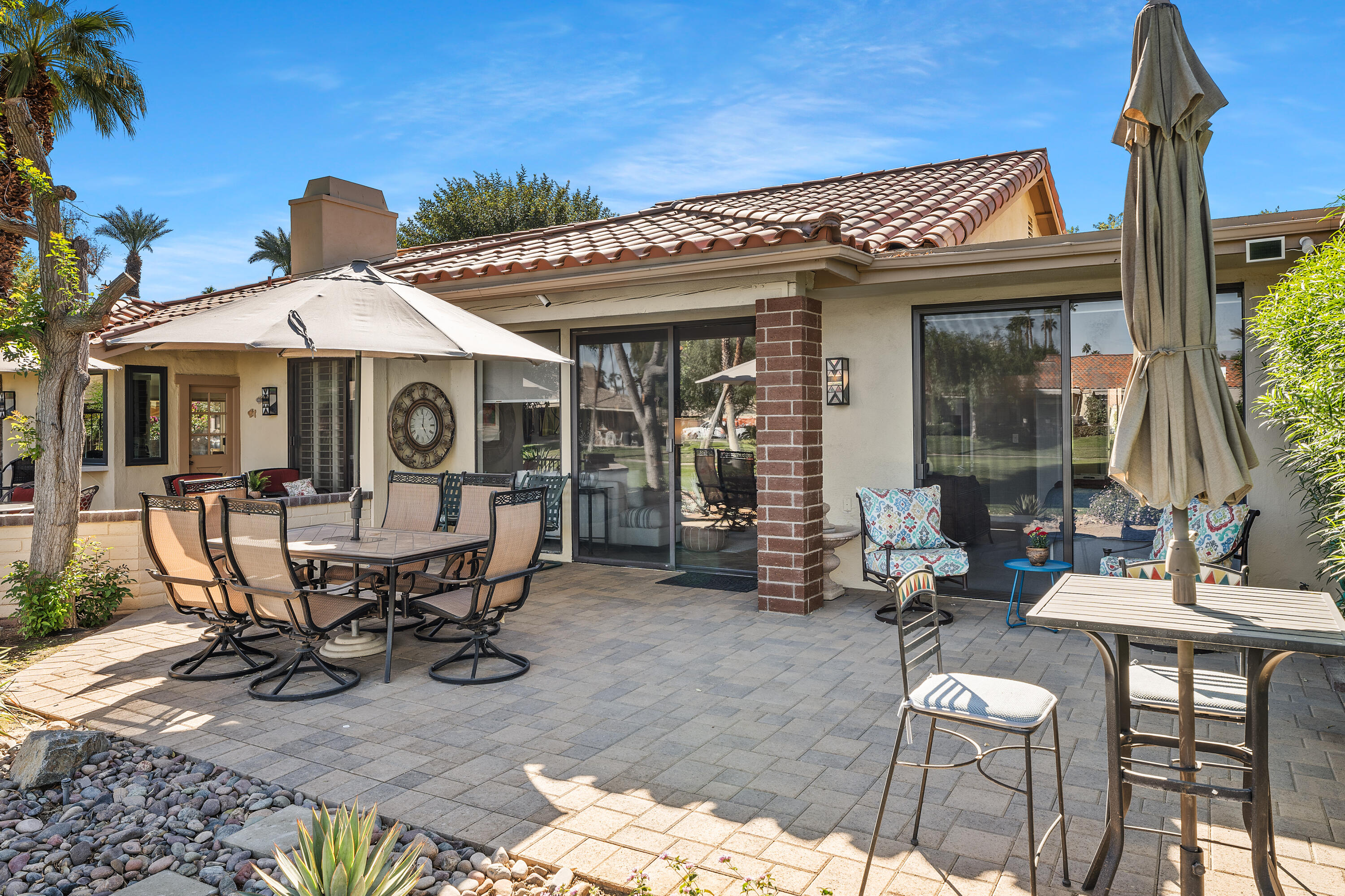 a view of a patio with table and chairs near a barbeque