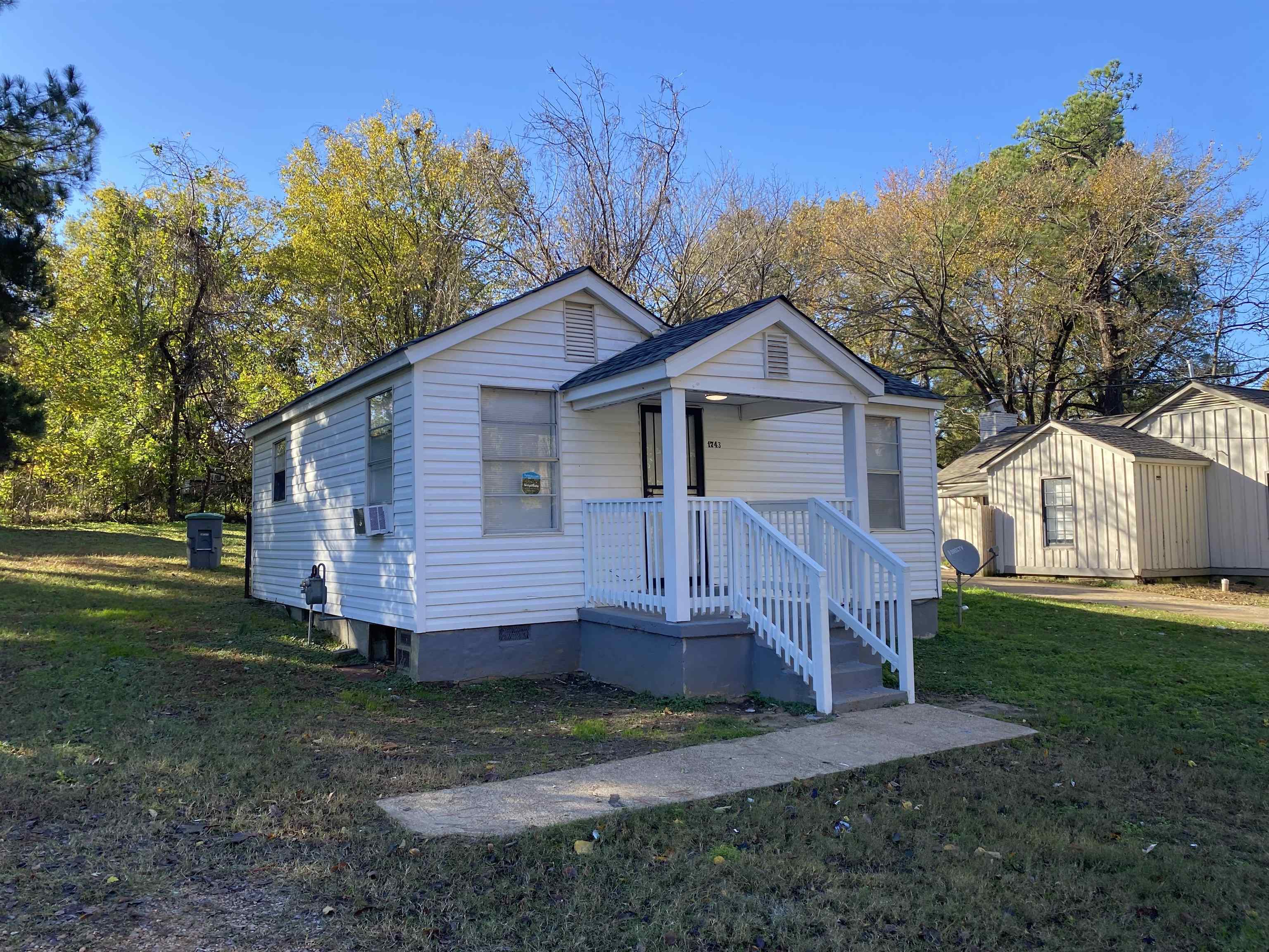 View of front facade with cooling unit, a storage shed, and a front yard