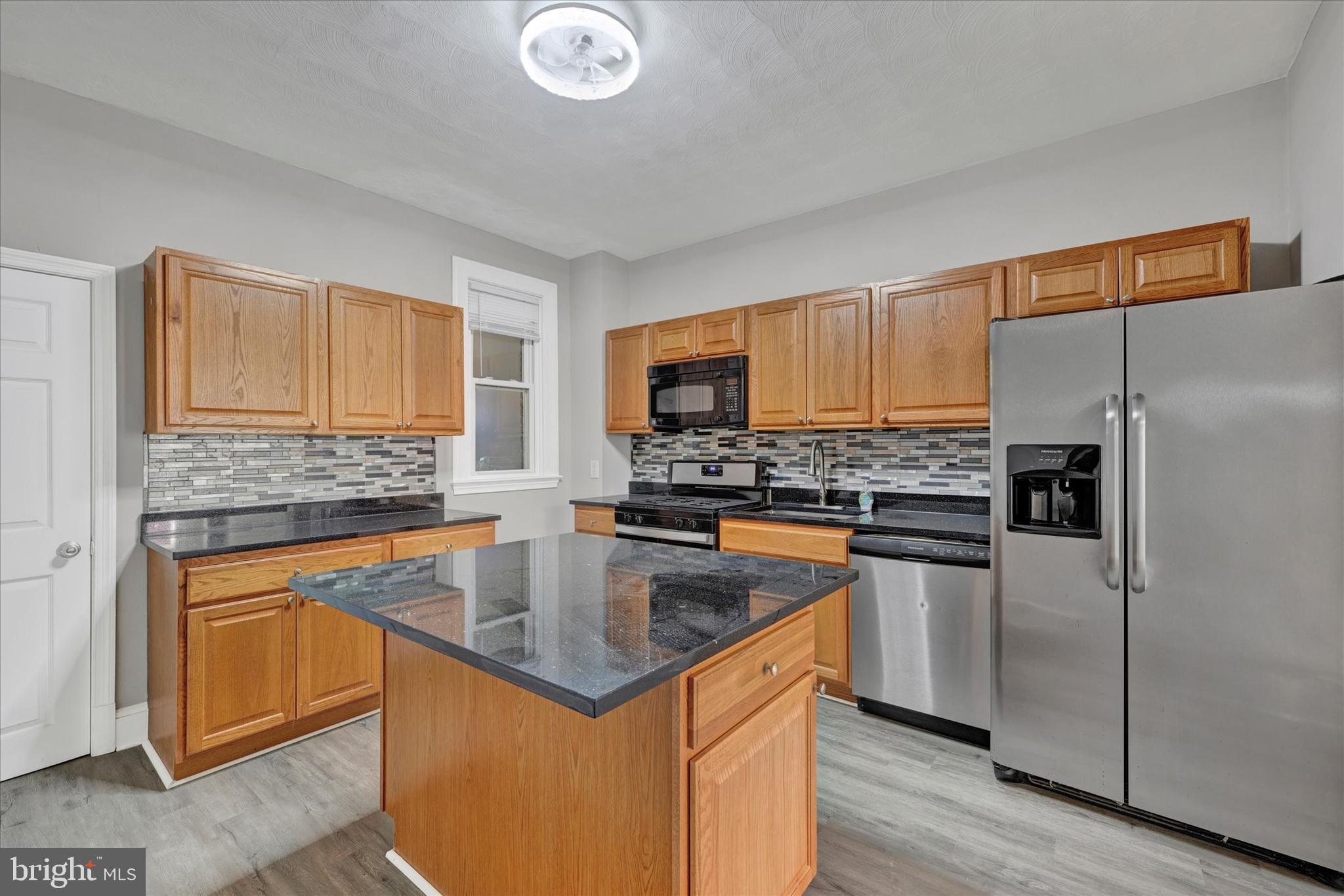 a kitchen with stainless steel appliances granite countertop a sink stove microwave and refrigerator