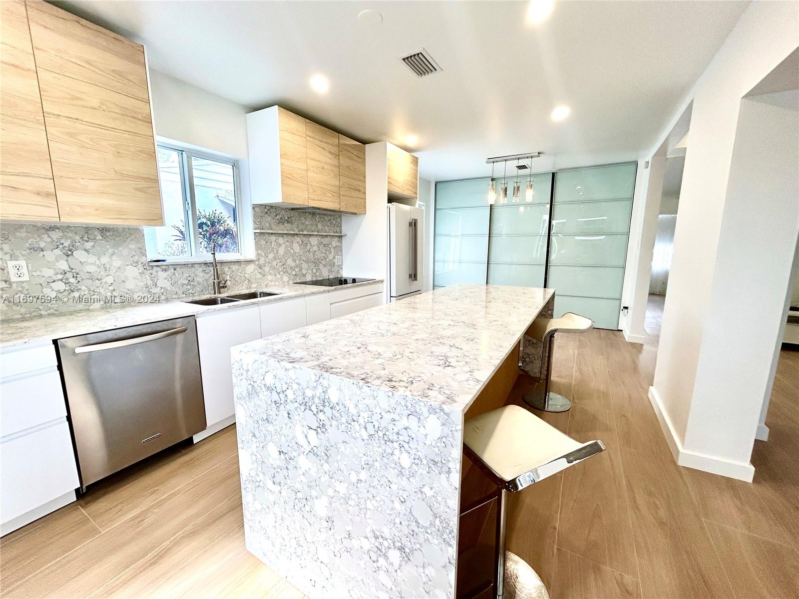 a kitchen with kitchen island a counter top space a sink stainless steel appliances and cabinets