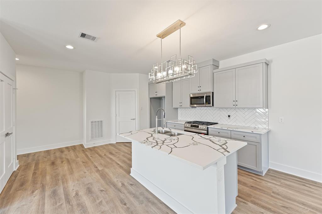 a kitchen that has a stove a sink and a wooden floor