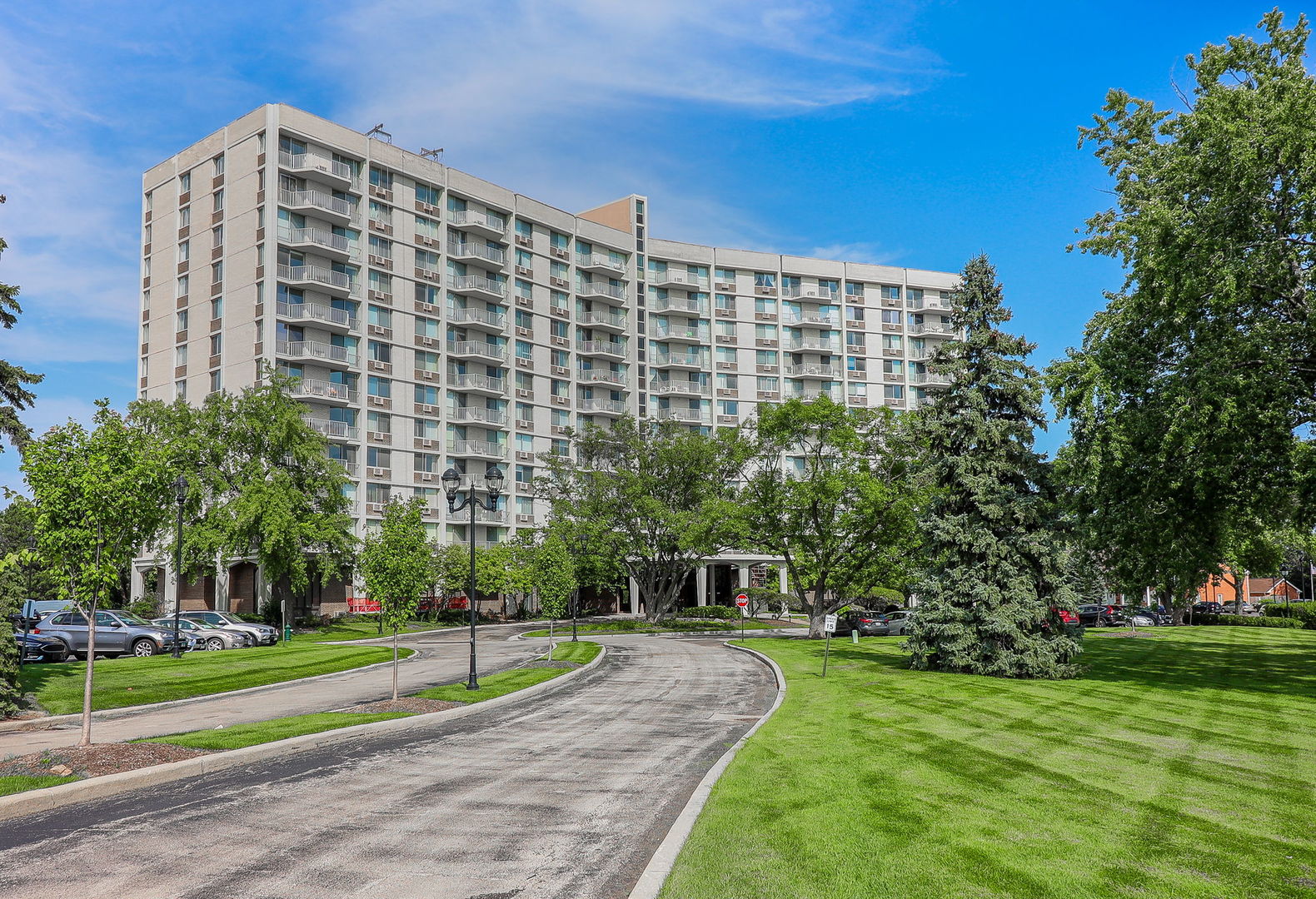 a view of a tall building next to a yard with big trees