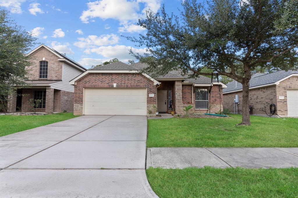 This is a single-family, one-story brick home with a two-car garage and a well-maintained lawn. It features a mature tree in the front yard and a covered entrance.