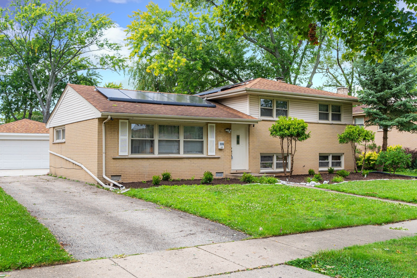 a front view of a house with a garden and trees