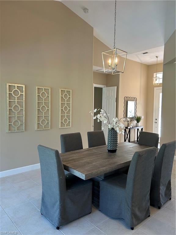 Tiled dining area featuring an inviting chandelier and high vaulted ceiling