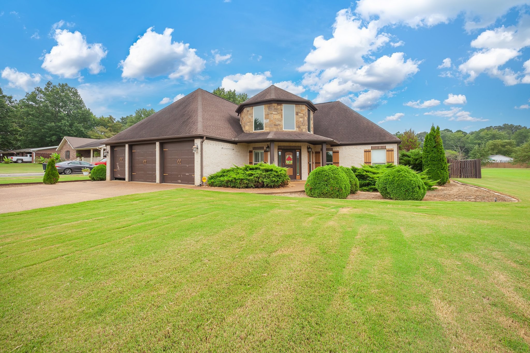 a view of a house next to a big yard and large trees