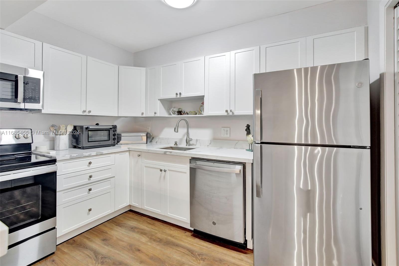 a kitchen with white cabinets white stainless steel appliances and wooden floors