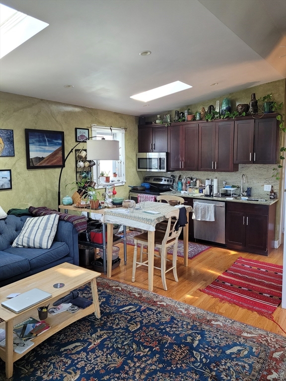 a living room with stainless steel appliances kitchen island a table and a couch