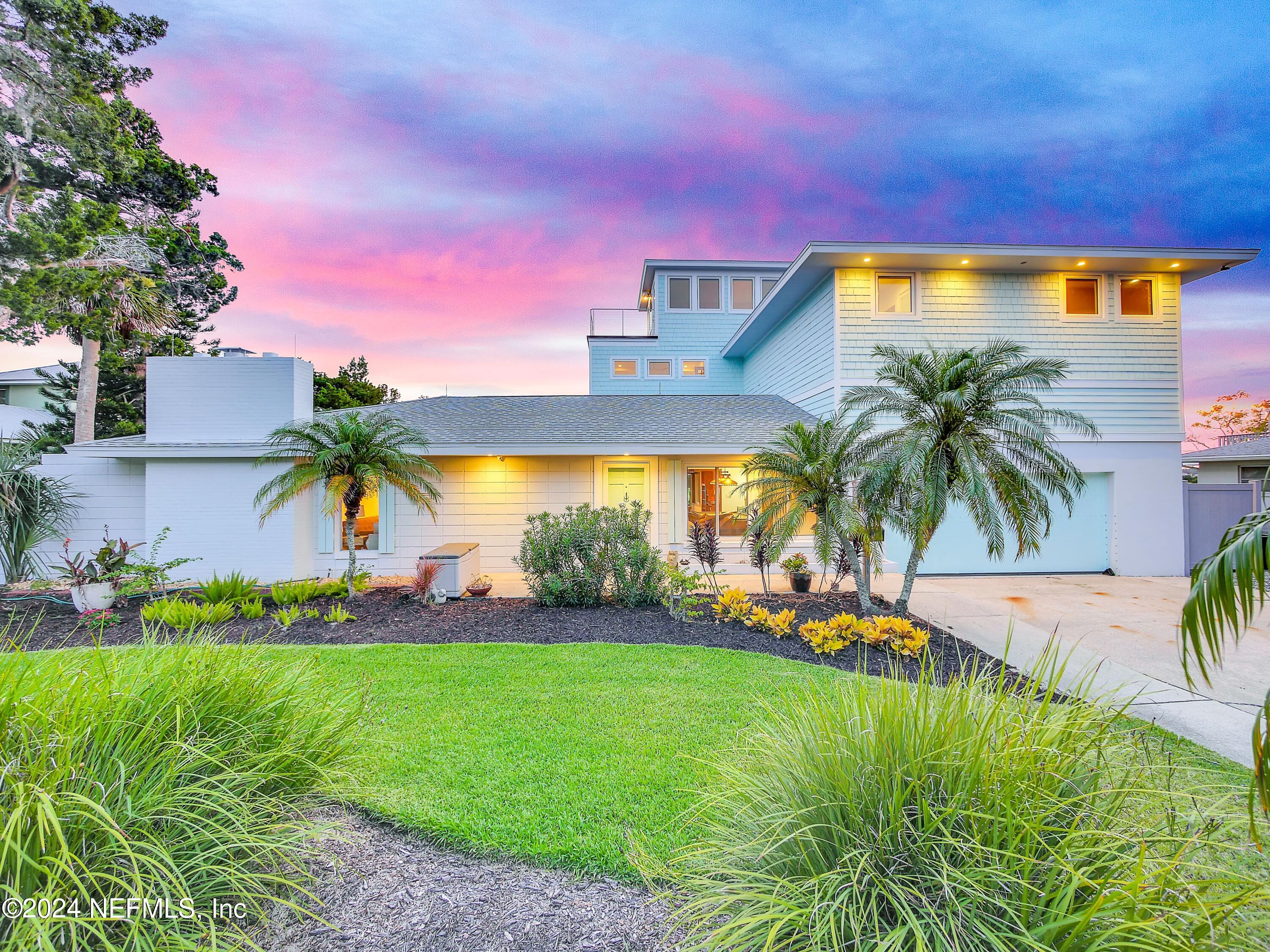 a palm tree sitting in front of a house with a yard